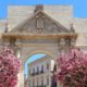 Lecce, Italy - city in Salento peninsula. Oleander flowers and Porta Napoli Triumphal Arch.